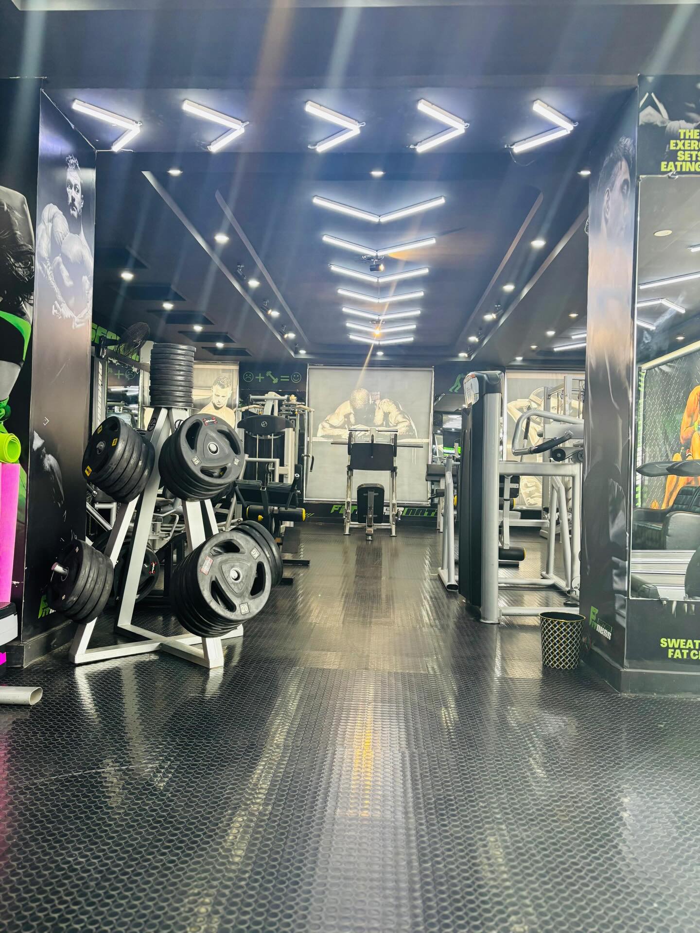 The main floor at Fitness Nation, lit by symmetric chevron LED strips running the length of the ceiling