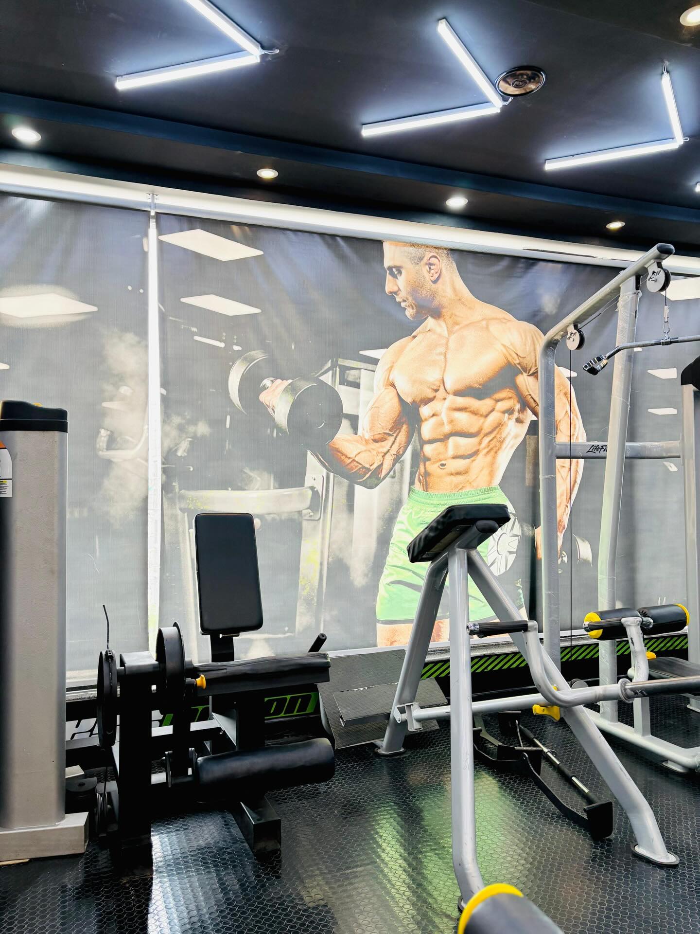 Free-weight benches and cable station under angled LED lighting